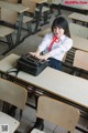 A woman sitting at a desk in a classroom.