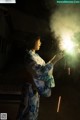 A woman in a kimono holding a sparkler in her hand.