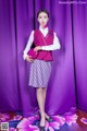 A woman in a pink vest and skirt posing for a picture.