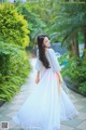A woman in a white dress standing in a garden.