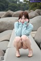 A woman sitting on a rock with her legs crossed.