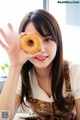 A woman holding a donut in front of her face.