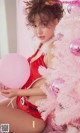 A woman in a red lingerie holding a pink balloon.