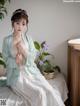 A woman sitting on top of a bed next to a plant.