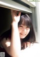 A young woman looking out of a window with her hand on the window sill.