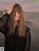 A woman with long hair standing on a beach.