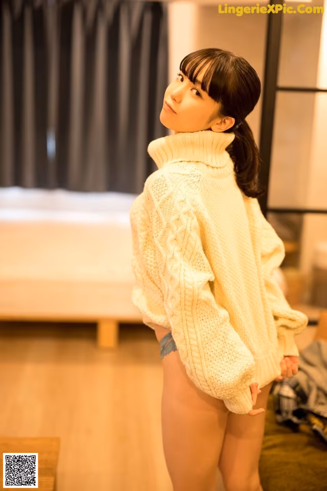 A woman in a white sweater is standing in a room.