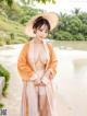 A woman in a pink kimono and a straw hat posing for the camera.