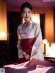 A woman in a white and red kimono standing on a bed.