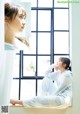 A woman sitting on a window sill looking out the window.