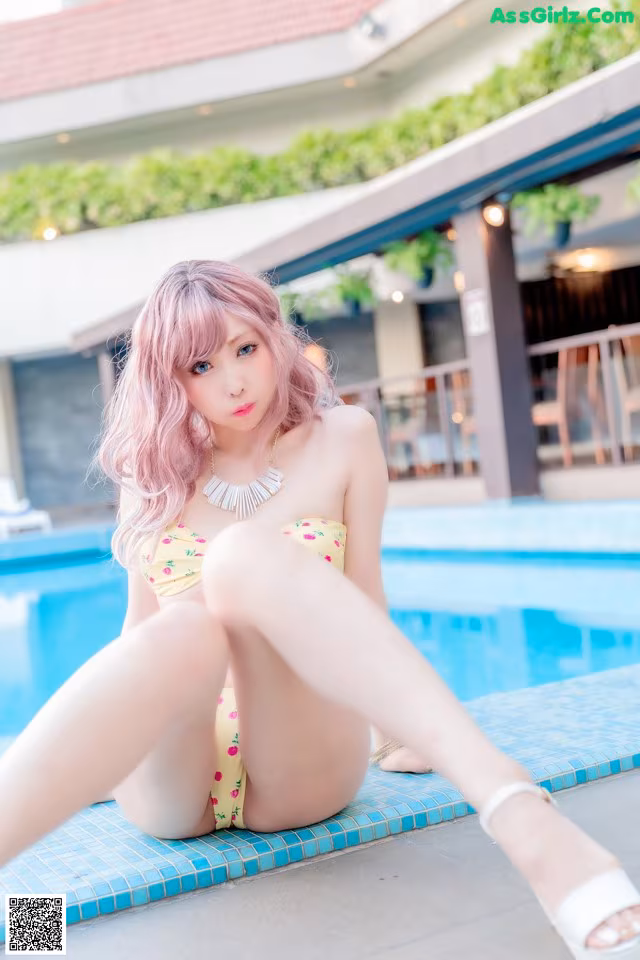 A woman in a bikini sitting by a swimming pool.