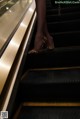 A woman in leopard print shoes is walking down an escalator.