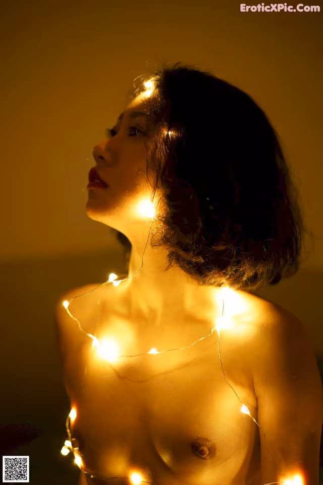 A naked woman with a string of lights around her neck.
